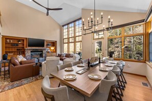 A spacious living area with a fireplace, a dining table set for six, and a large window offering a view of the outdoors. - Spectacular views | Private Hot Tub | Sleeps 16 (Beaver Creek)