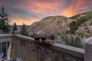 A balcony with a tray holding two glasses of red wine, overlooking a mountainous landscape with trees and a sunset. - Spectacular views | Private Hot Tub | Sleeps 16 (Beaver Creek)