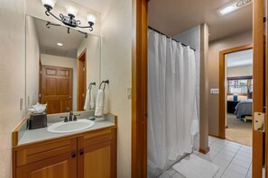 A bathroom with a wooden vanity, a large mirror, a white sink, and a shower curtain. - Spectacular views | Private Hot Tub | Sleeps 16 (Beaver Creek)