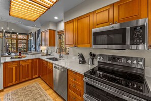 A modern kitchen with wooden cabinets, stainless steel appliances, and a large window. - Spectacular views | Private Hot Tub | Sleeps 16 (Beaver Creek)