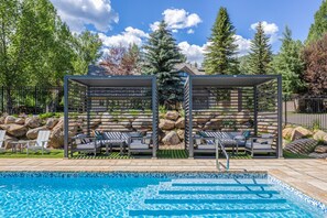 A swimming pool with lounge chairs and a covered seating area.