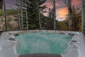 Ein Whirlpool mit Blick auf einen Wald und einen Sonnenuntergang.