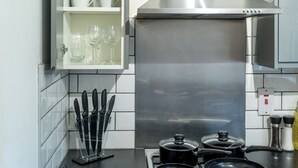 A modern kitchen with white tiles, stainless steel appliances, and a knife block. - Pet-friendly 1-bedroom Apartment in Crawley (Crawley)