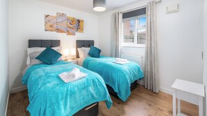 A hotel room with two beds, a window with curtains, a radiator, and artwork on the wall. - Pet-friendly 1-bedroom Apartment in Crawley (Crawley)