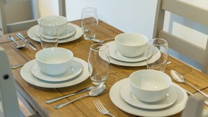 A dining table set with white plates, bowls, and clear glasses, accompanied by silverware. - Pet-friendly 1-bedroom Apartment in Crawley (Crawley)
