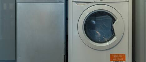 Two front-loading washing machines, one silver and one white, with control panels and labels.