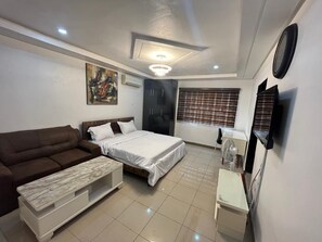 Relax in a spacious bedroom with a large bed, comfortable sofa, and convenient bedside table.