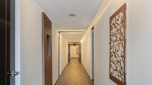 Un long couloir étroit, doté d’un plancher en bois et de murs blancs, qui mène à une porte au bout.