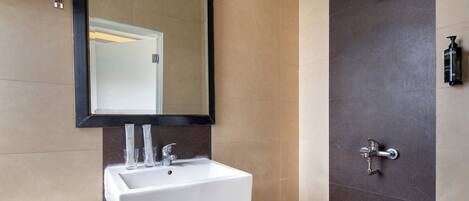 A bathroom with a white sink, a mirror, a shower, and a toilet.