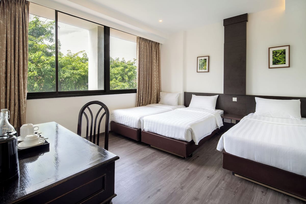 A hotel room with two beds, a desk, and a large window with curtains.