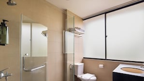 Une salle de bain moderne avec une douche à l’italienne en verre, des toilettes blanches et un lavabo noir.