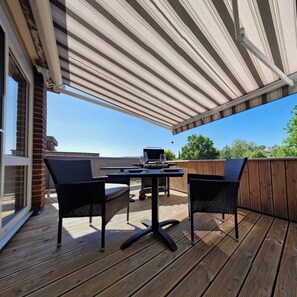 An outdoor patio with a covered seating area, a grill, and a view of the surrounding landscape. - Vacation Rental in Wiehl, 50 m², Sun Terrace, 2 Guests (Wiehl)