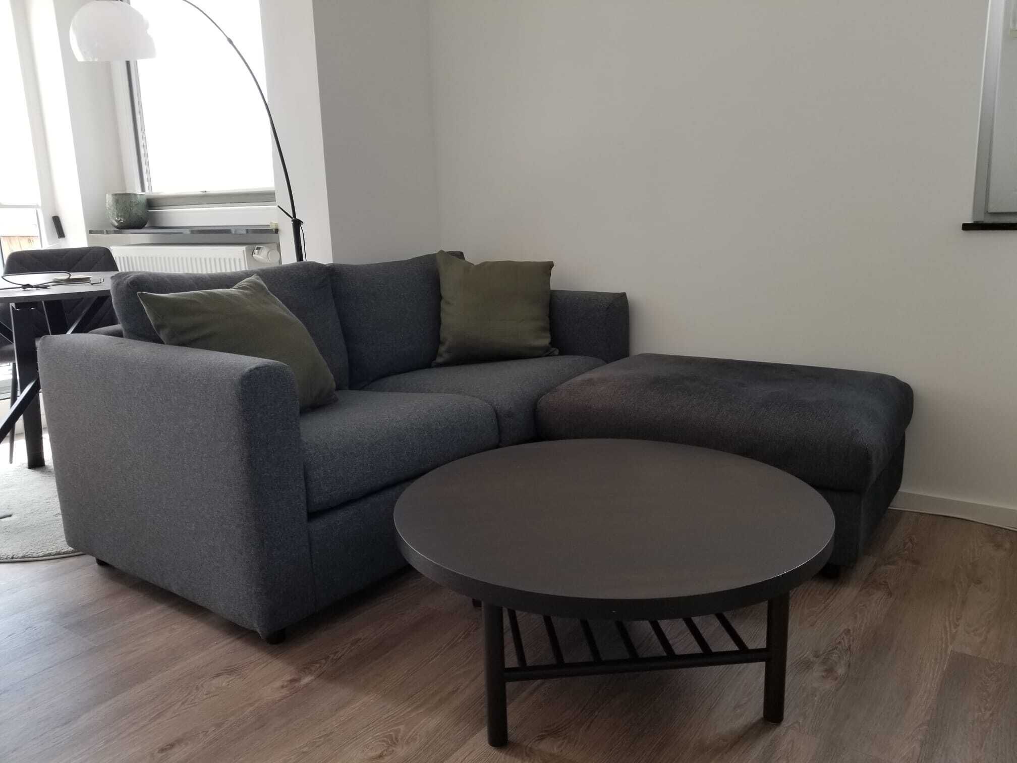 A modern living room with a grey sectional sofa, a round coffee table, and a small side table.