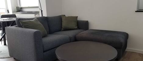A modern living room with a grey sectional sofa, a round coffee table, and a small side table.