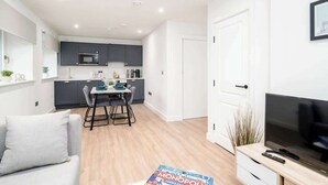 Una sala de estar moderna con un sofá, un comedor, una cocina y un televisor.