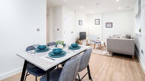 Una sala de estar moderna con comedor, un sofá y un televisor.