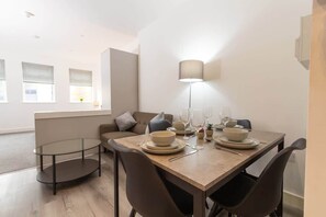 A dining area with a table set for four, a sofa, and a lamp. - Cosy 1Bed Getaway in Central Hull (Hull)