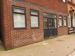 A red brick building with large windows and a black door.