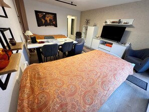 A hotel room with a large bed, a desk with chairs, a television, and a world map on the wall. - Charming vacation apartment in Bergstein, Hürtgenwald  (Hürtgenwald)