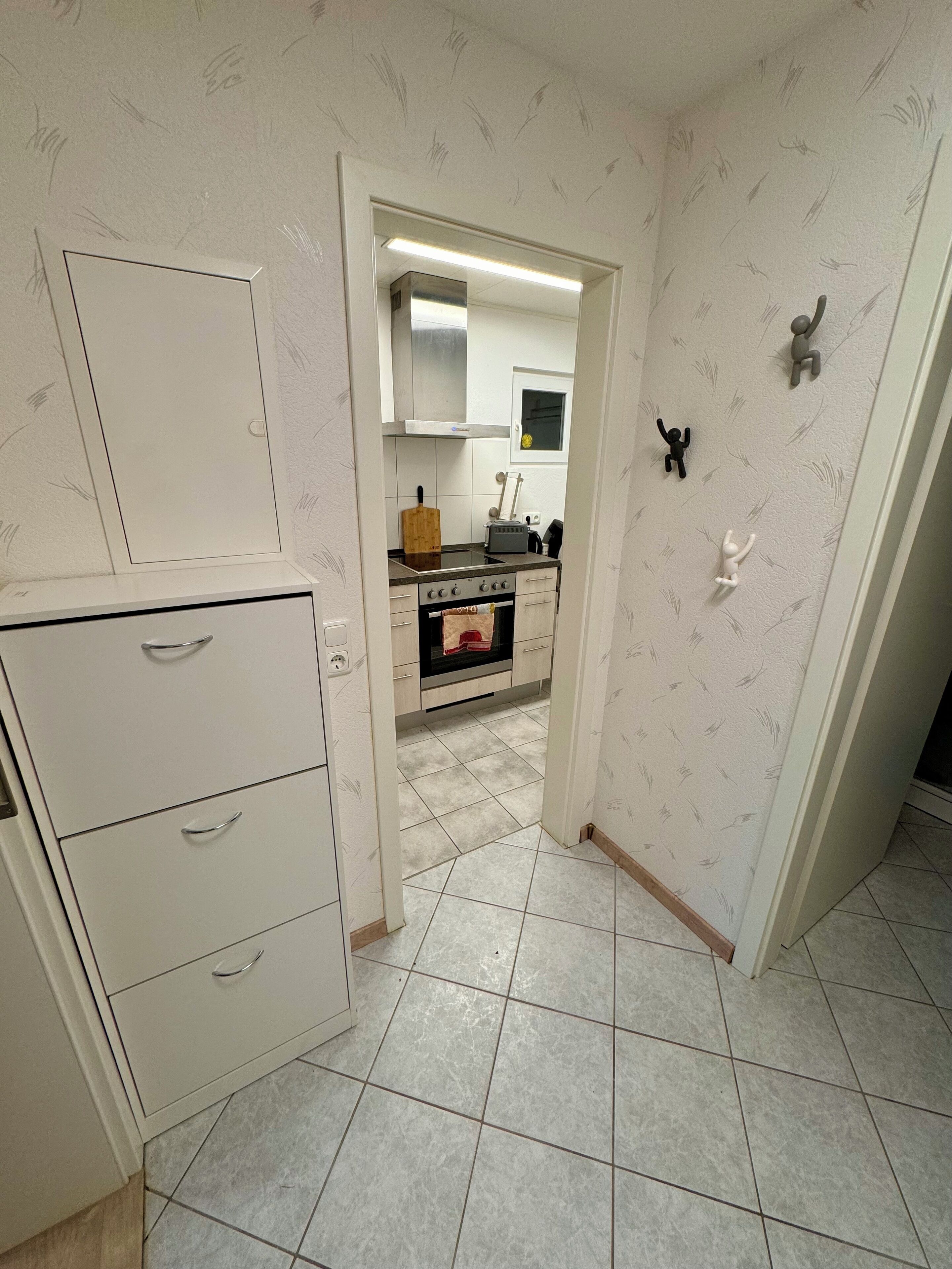 A compact kitchen with a built-in oven, a microwave, and a toaster. There is a cabinet with drawers and a small countertop.