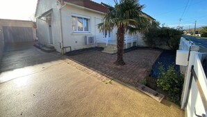 A residential house with a paved driveway, a palm tree, and a garage.