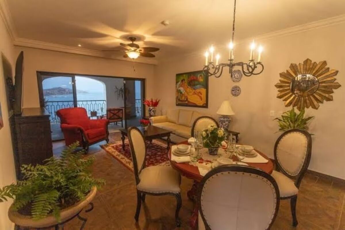 A dining area with a table set for four, a red armchair, and a sofa.