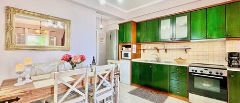 Una cocina moderna con armarios verdes, una mesa de comedor con sillas y una araña.