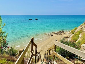 A wooden staircase leading down to a beach with clear turquoise water and rocky outcrops. - Beachfront Villa Rania with private pool (Chalikounas)