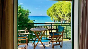 A balcony with a wooden table and chairs, overlooking a pool and a clear blue sea. - Beachfront Villa Rania with private pool (Chalikounas)