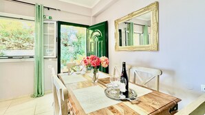 A dining area with a wooden table, chairs, a mirror, and a window with a view of greenery. - Beachfront Villa Rania with private pool (Chalikounas)