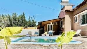 Ein Swimmingpool mit Liegestühlen und einer überdachten Terrassenfläche.
