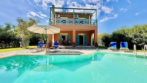 A two-story building with a pool, outdoor seating, and a clear sky. - Beach Villa Simeoni with private pool (Lefkada)