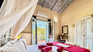 A bedroom with a bed, a nightstand, a wardrobe, and a balcony with a view. - Beach Villa Simeoni with private pool (Lefkada)