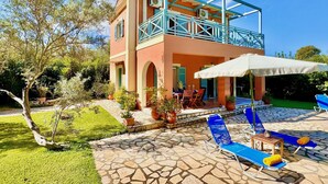 A two-story building with a balcony, outdoor seating area, and a garden. - Beach Villa Simeoni with private pool (Lefkada)