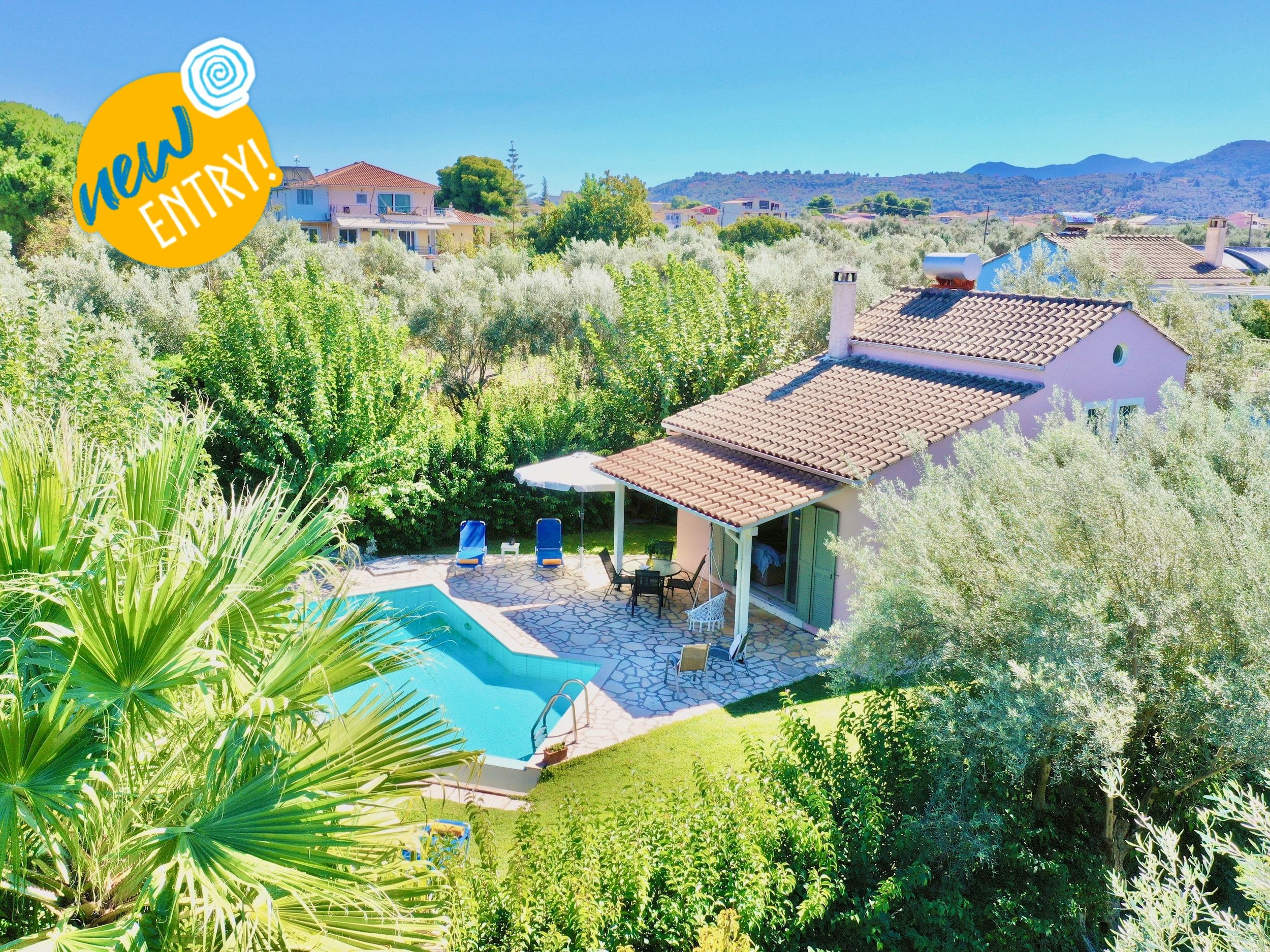 A residential property with a swimming pool, patio, and surrounding greenery.