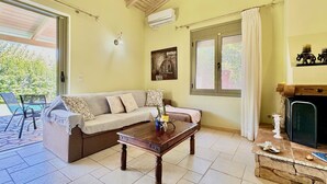 A living room with a sofa, a coffee table, a fireplace, and a large window with curtains. - Beach Villa Fotini with private pool (Lefkada)