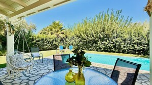 A covered outdoor area with a pool, seating, and a view of the surrounding greenery. - Beach Villa Fotini with private pool (Lefkada)