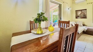 A dining area with a wooden table, chairs, a vase with flowers, and a window with curtains. - Beach Villa Fotini with private pool (Lefkada)