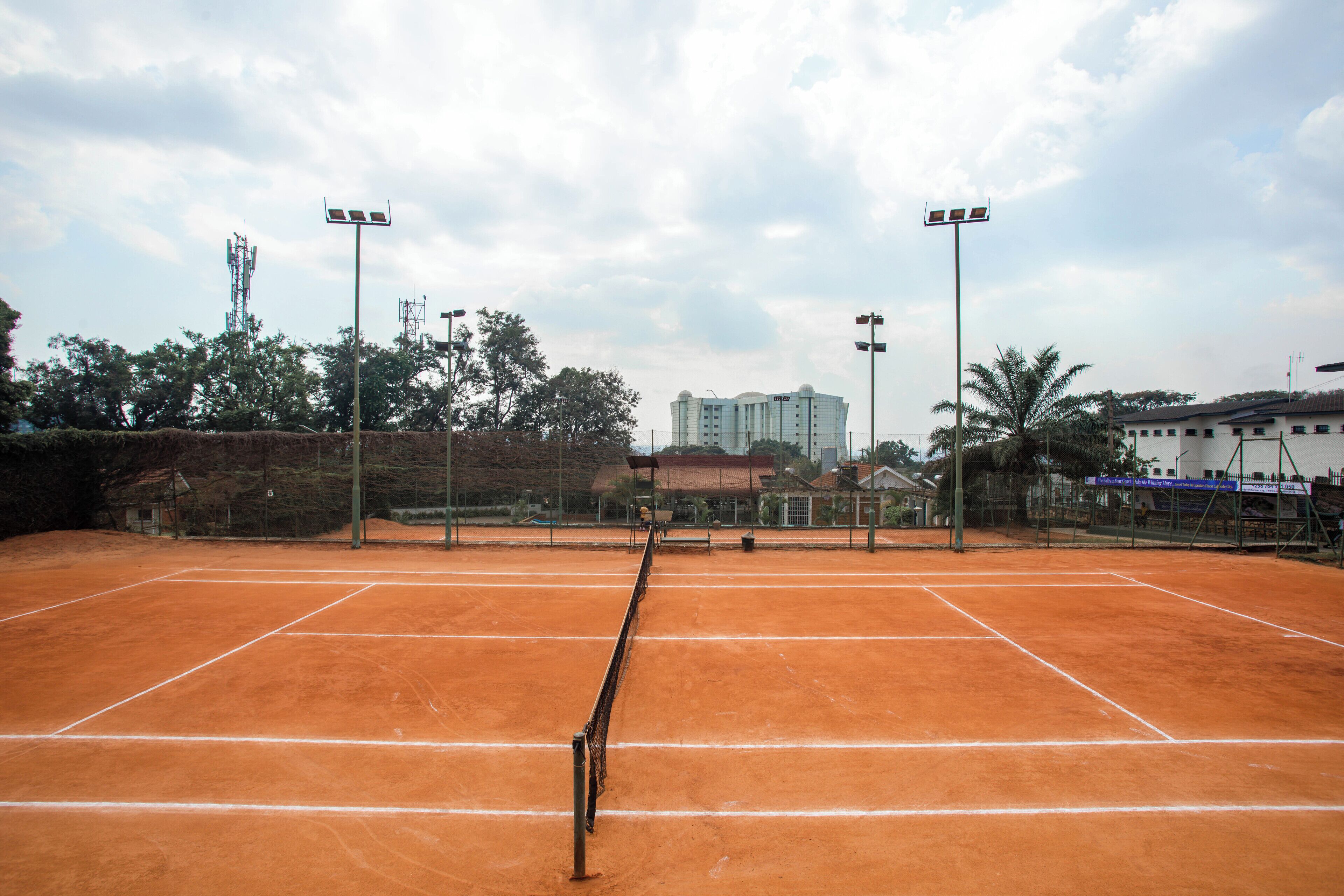Una pista de tennis amb una xarxa, envoltada d'arbres i edificis.