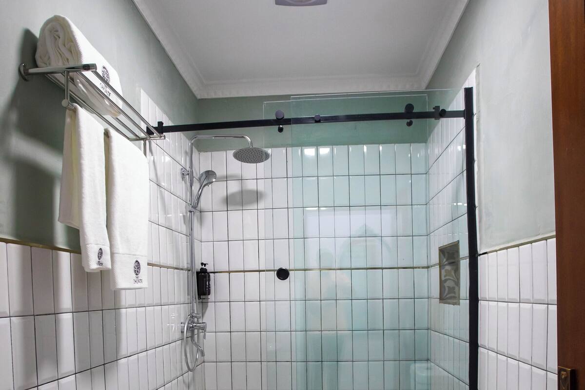 A small, tiled bathroom with a shower, toilet, and sink.