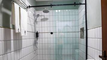 Een kleine badkamer met tegels, voorzien van een douche, toilet en wastafel.