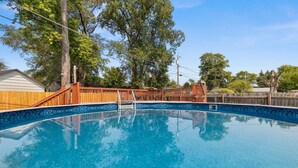 A clear blue swimming pool with wooden deck and metal ladder, surrounded by trees and a wooden fence. - Poolside Palisade - A Fun Family Retreat for 6 (Marquette Heights)
