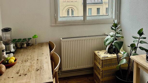 A corner room with a wooden table, chairs, a radiator, a window with a view of buildings, and a potted plant. - Charming townhome with 2 bedrooms and AC, WiFi in lovely Suffolk Park (Suffolk Park)