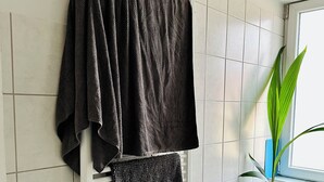 A bathroom with a white radiator, a towel rack with a folded towel, a potted plant, and a shelf with toiletries. - Charming townhome with 2 bedrooms and AC, WiFi in lovely Suffolk Park (Suffolk Park)