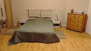 Un dormitorio con cama, mesitas de noche, cómoda y espejo.