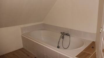 Une salle de bain avec une baignoire sur pieds, des murs carrelés et un plancher en bois.