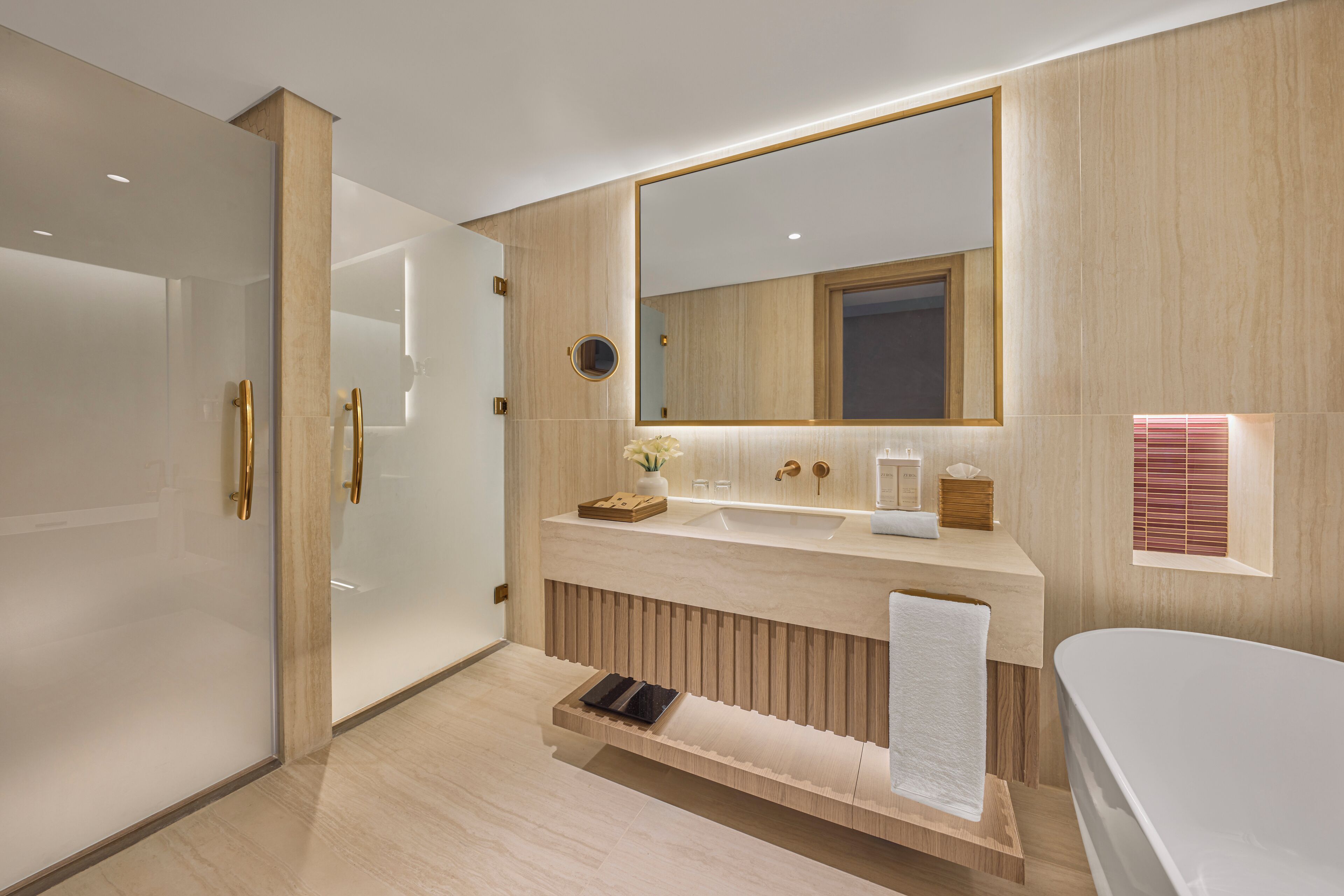 Un baño moderno con un espejo grande, una bañera, un tocador con lavabo y un perchero para toallas.