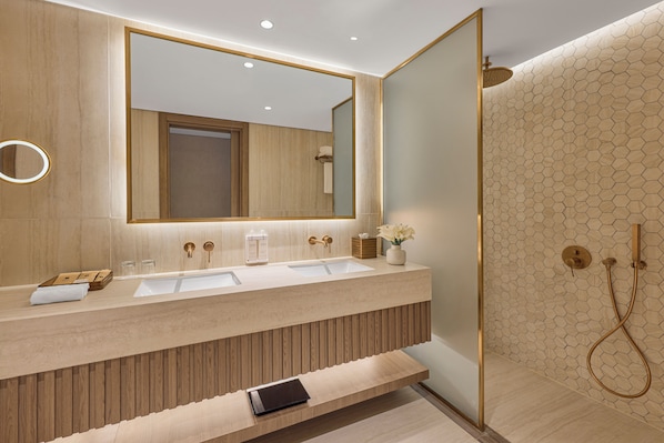 Un baño moderno con un espejo grande, dos lavamanos, una ducha y un mueble de tocador de madera.