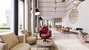 A modern living room with a large window, a red armchair, and a sofa. There is a dining area in the background. - Makarem Burj Al Madinah Hotel and Suites (Madinah)