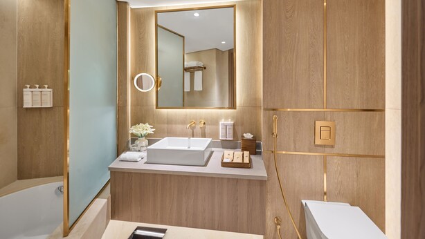 A modern bathroom with a large mirror, a sink, a bathtub, and a toilet.